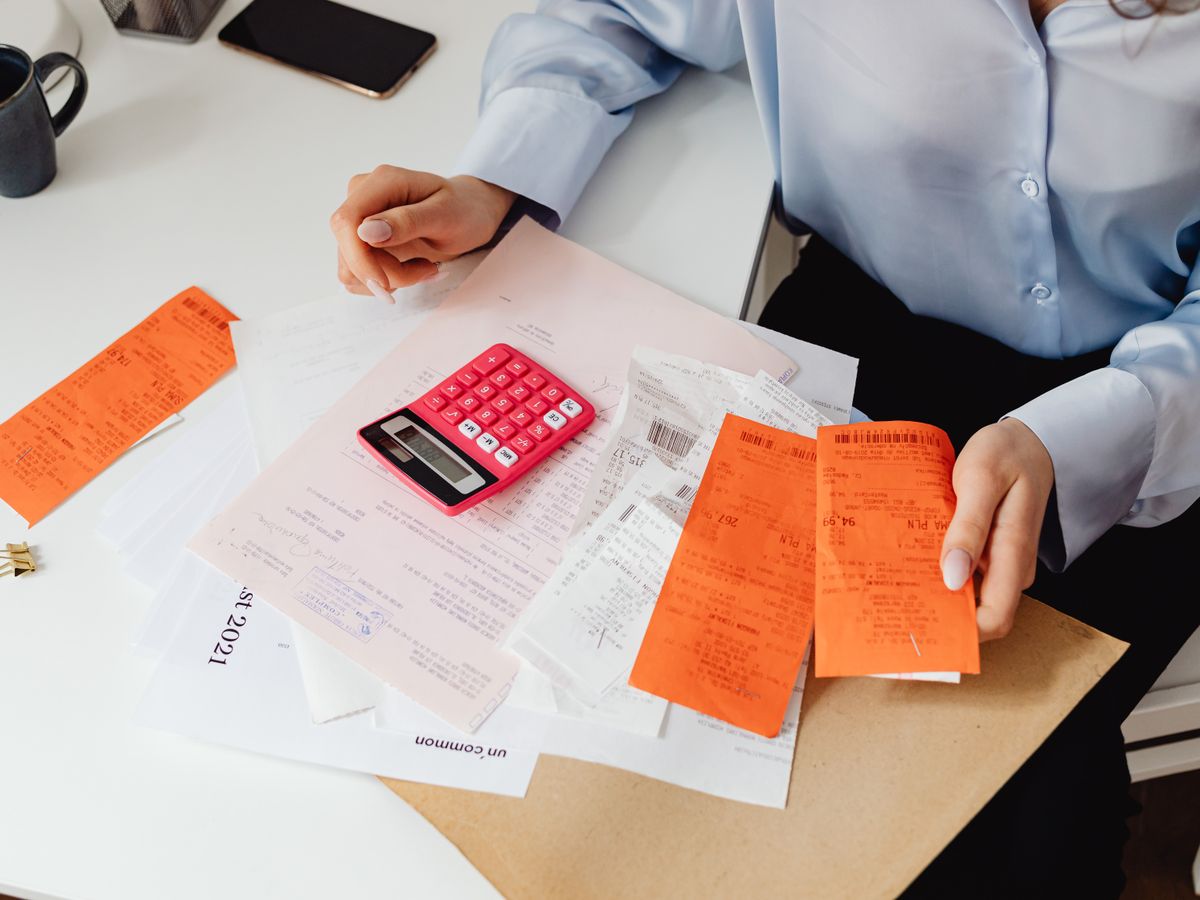 Bookkeeper sorting a stack of receipts and paper statements at a desk