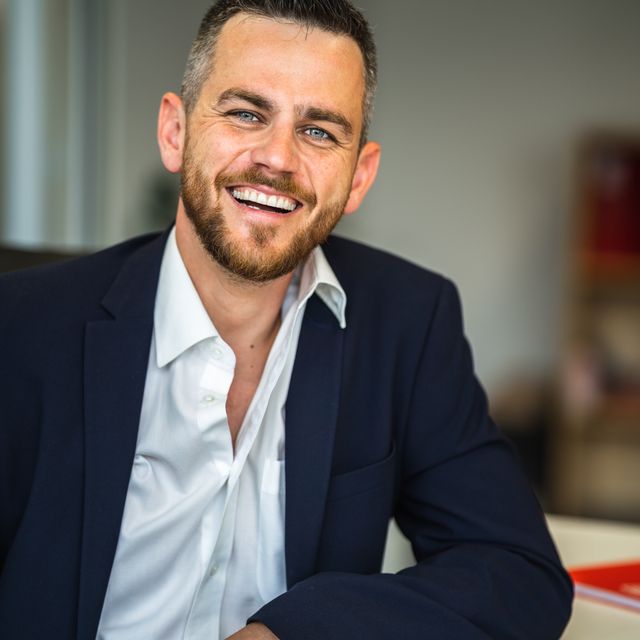 Laughing professional in a navy blazer at an office desk